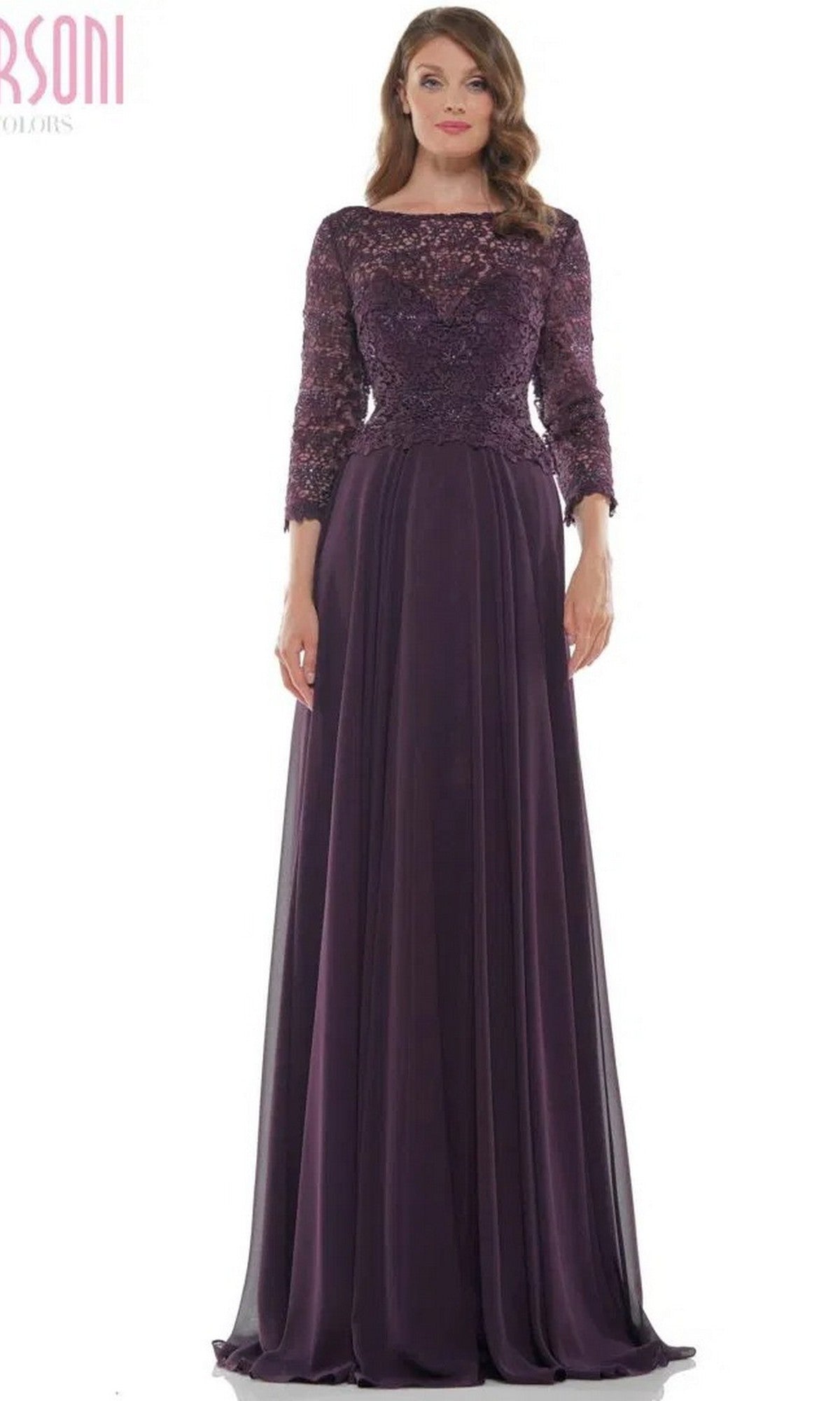 A woman wears the Marsoni M223 long formal dress in eggplant, featuring lace embroidery, long sleeves, and a flowing chiffon skirt.